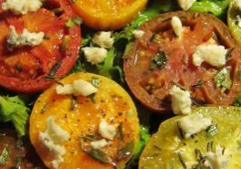 Close-up of colorful roasted tomatoes topped with crumbled cheese and herbs.