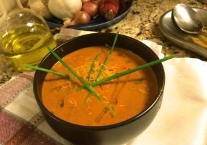 A bowl of creamy tomato soup garnished with chives.