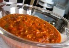A bowl of rich tomato-based stew with herbs and spices.