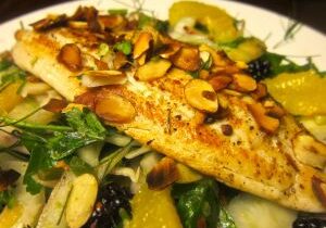 Grilled fish fillet topped with toasted almonds on a fresh salad.