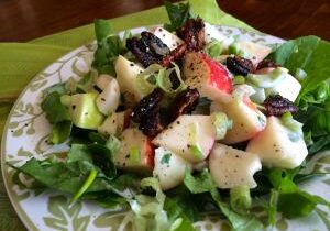 Fresh mixed green salad with apples and red onions.