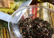 A glass bowl filled with dried tea leaves on a striped cloth.